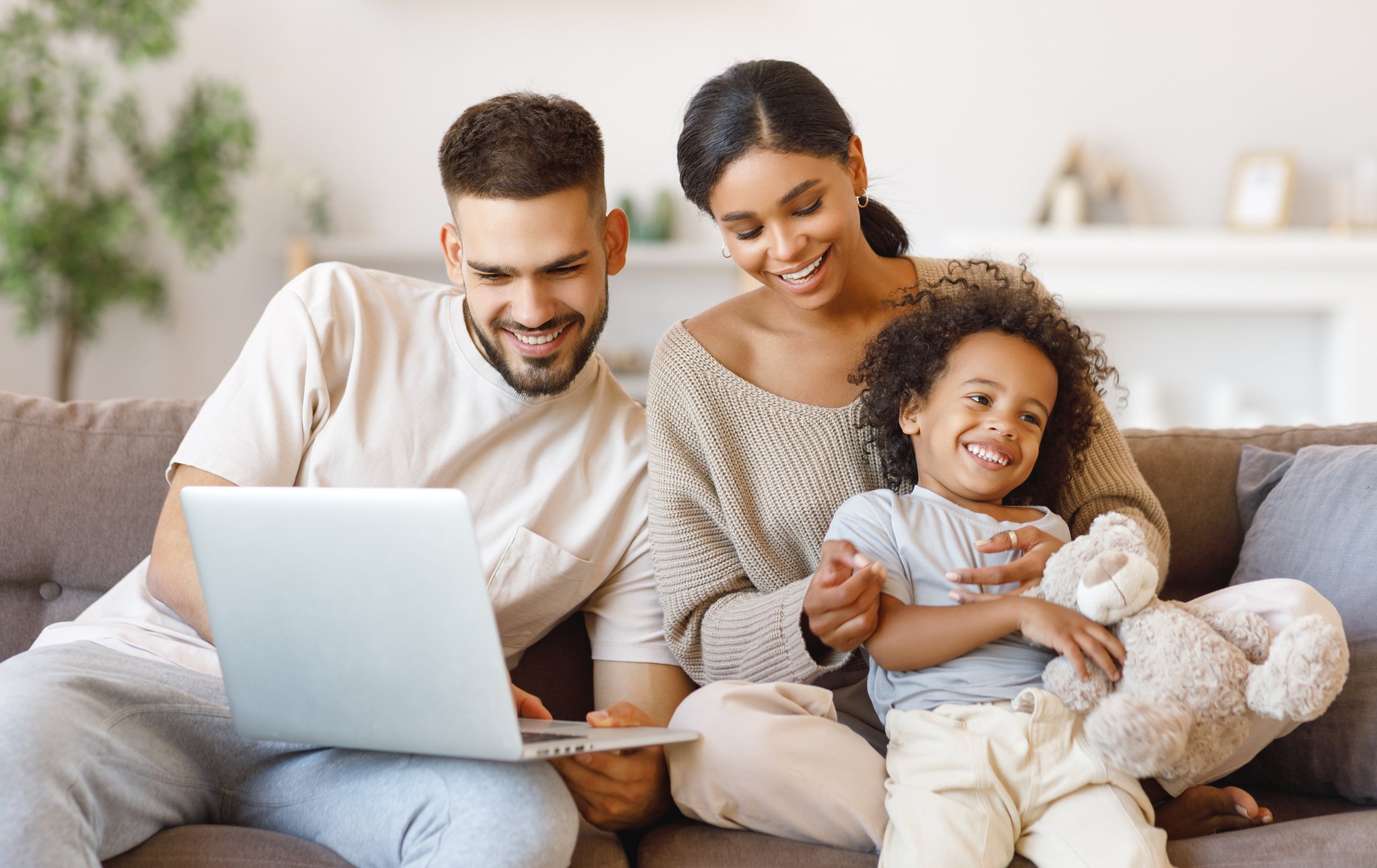 Diverse family using laptop on sofa together